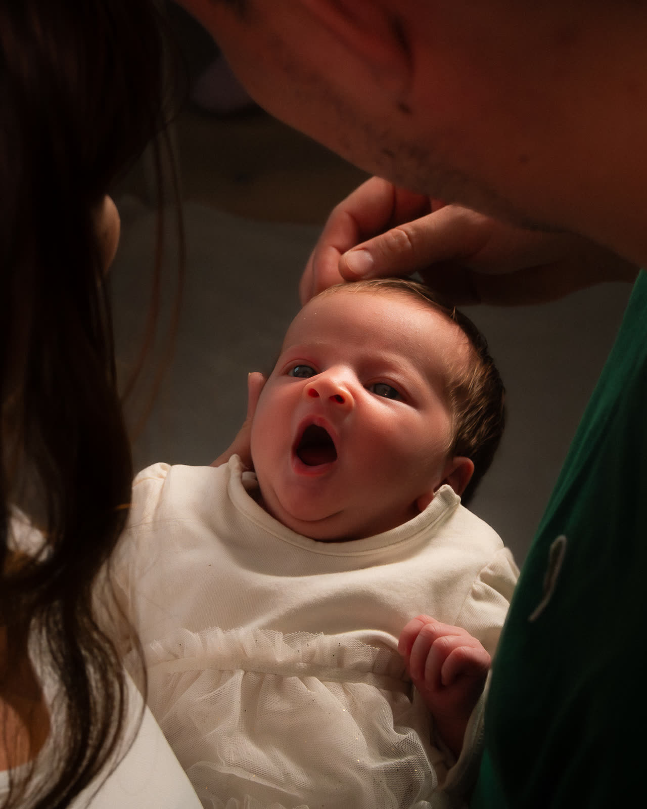 Bebé recién nacido bostezando en brazos de sus padres