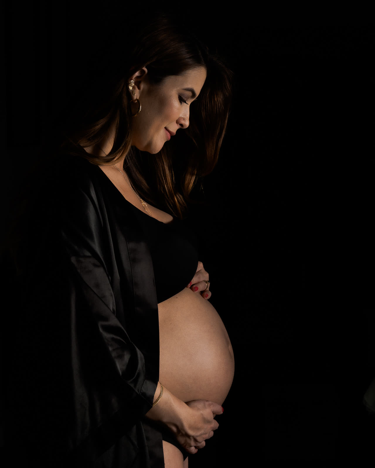 Retrato de maternidad en clave baja sobre fondo negro