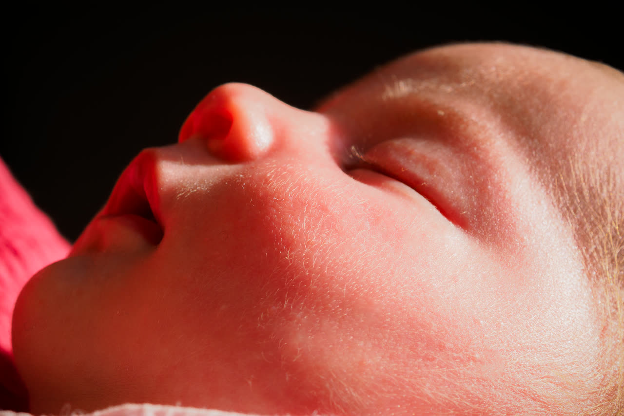 Primer plano del rostro de un bebé dormido con luz cálida