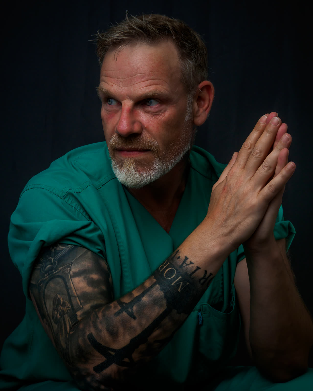 Retrato de un profesional de la salud con las manos juntas sobre fondo oscuro