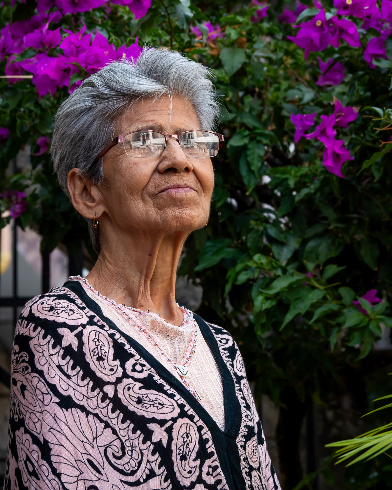 Retrato de una mujer mayor frente a buganvillas moradas