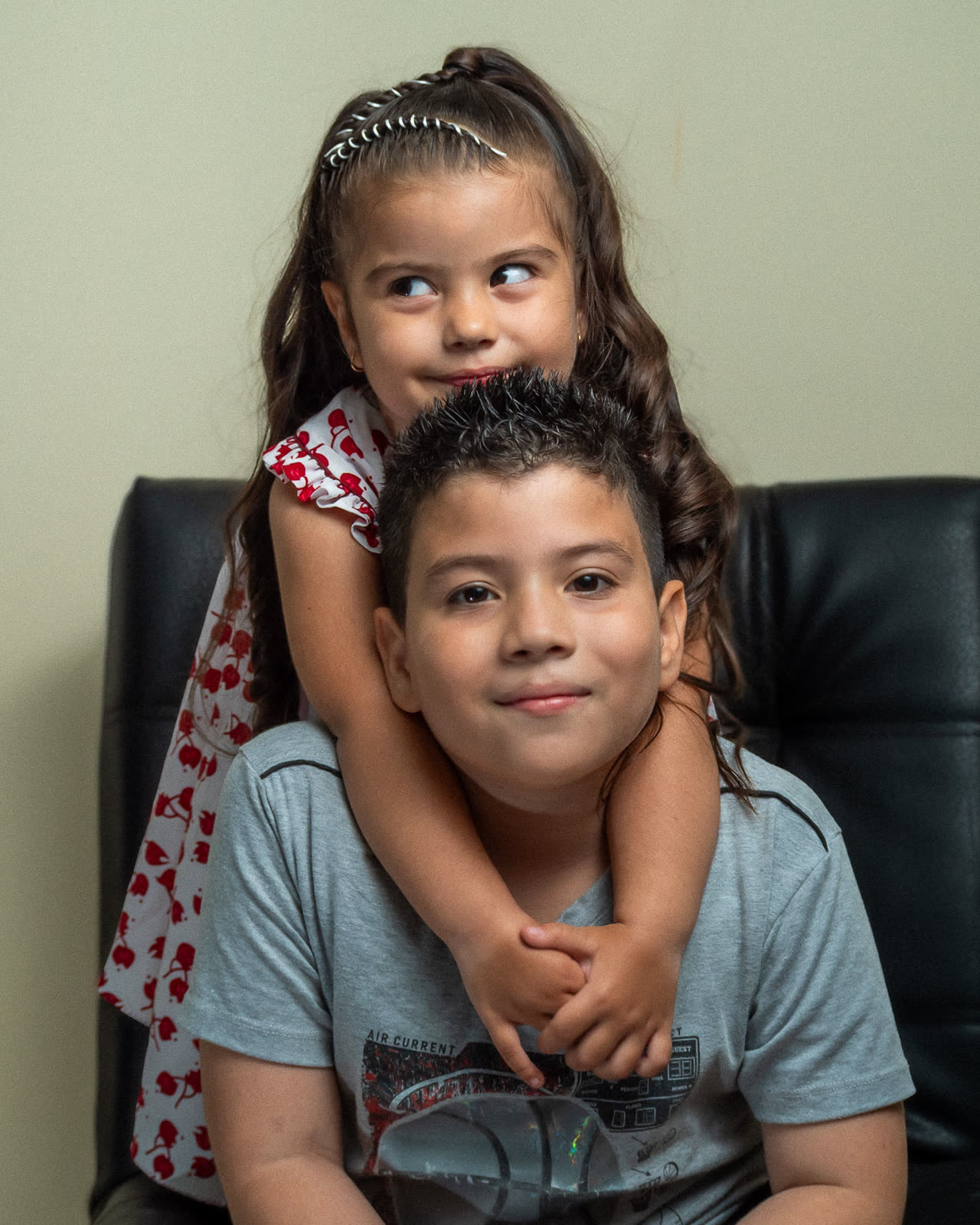 Dos hermanos abrazados sonriendo en un retrato de familia