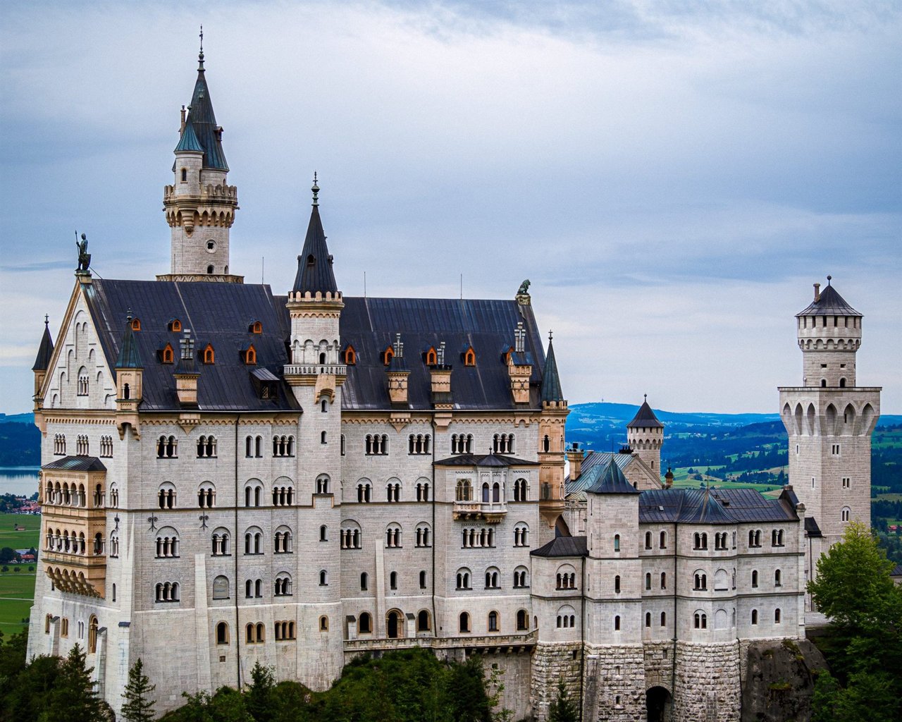 Castillo de Neuschwanstein entre bosques bajo un cielo nublado