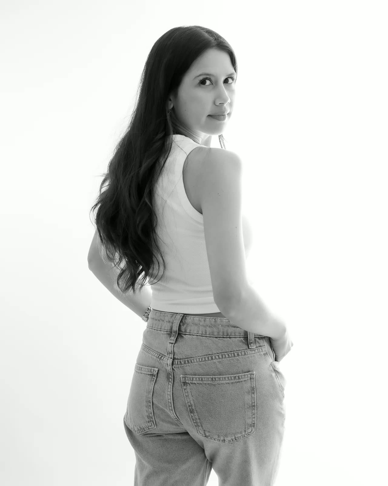 Retrato en blanco y negro de una mujer de espaldas con vaqueros, mirando por encima del hombro