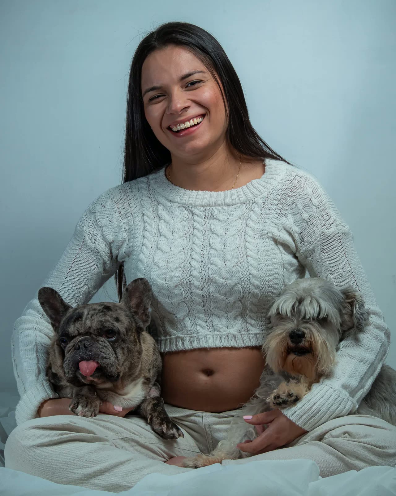 Mujer embarazada sonriente sentada en el suelo con sus dos perros